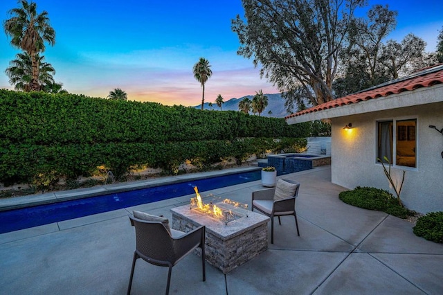 pool at dusk featuring a mountain view and an outdoor fire pit