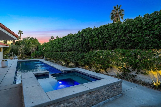 pool at dusk with an in ground hot tub