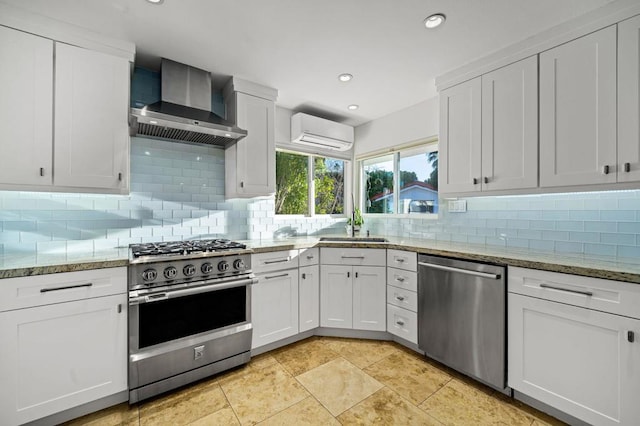 kitchen featuring a wall mounted AC, white cabinets, stainless steel appliances, light stone countertops, and wall chimney range hood