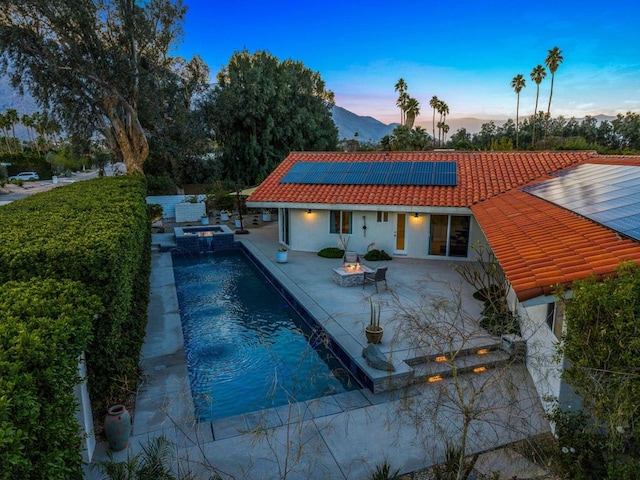 pool at dusk featuring a patio and an outdoor fire pit