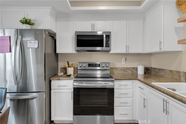 kitchen with stainless steel appliances, sink, white cabinets, and stone counters