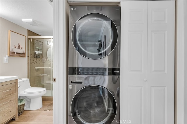 laundry room featuring stacked washer / drying machine and wood-type flooring