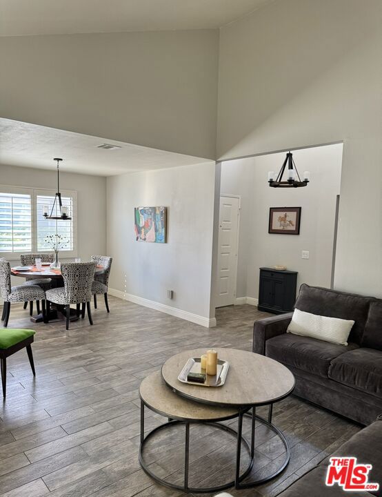 living room featuring an inviting chandelier, hardwood / wood-style floors, and high vaulted ceiling