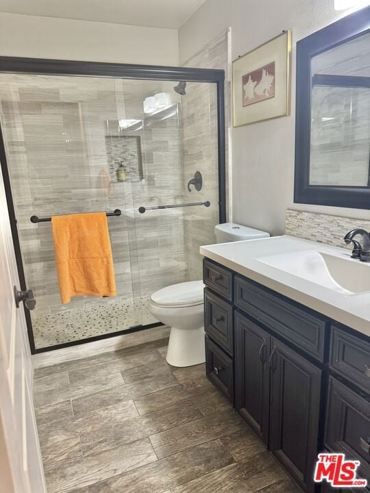 bathroom with vanity, an enclosed shower, tasteful backsplash, and toilet