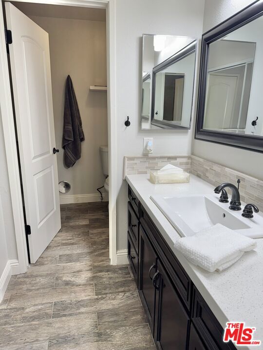 bathroom with vanity, backsplash, wood-type flooring, and toilet