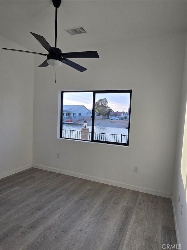 empty room featuring wood-type flooring, ceiling fan, and a water view