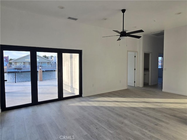 empty room featuring hardwood / wood-style flooring, a towering ceiling, and ceiling fan