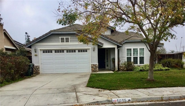 view of front of property with a front yard, stone siding, driveway, and an attached garage