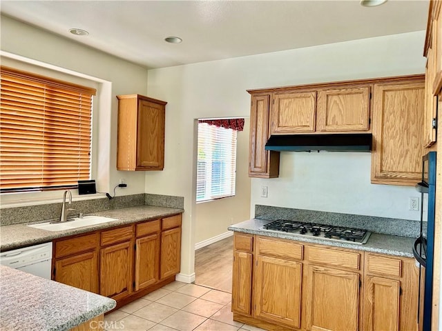 kitchen with light tile patterned floors, dishwasher, under cabinet range hood, stainless steel gas cooktop, and a sink