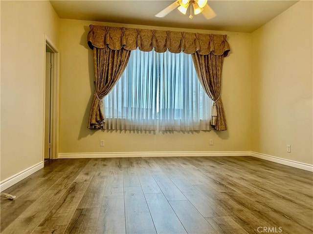 spare room with a ceiling fan, baseboards, and wood finished floors