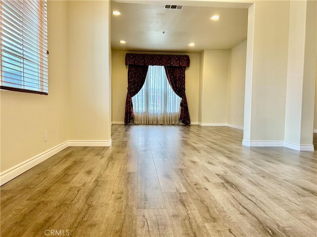 unfurnished room with baseboards, visible vents, wood finished floors, and recessed lighting