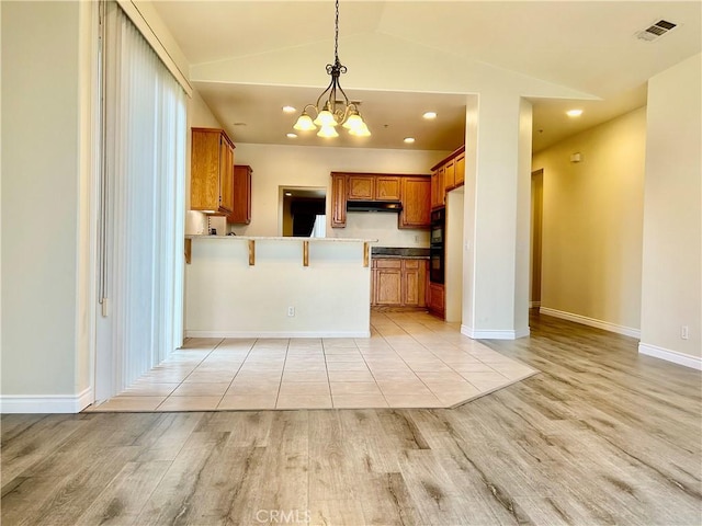 kitchen with lofted ceiling, visible vents, an inviting chandelier, brown cabinetry, and a peninsula