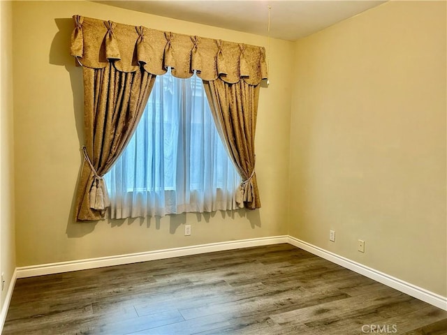 unfurnished room with dark wood-style flooring and baseboards