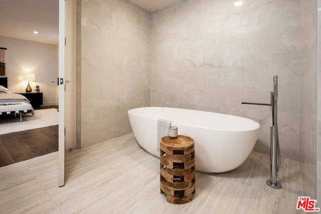 bathroom with a bathing tub and tile walls