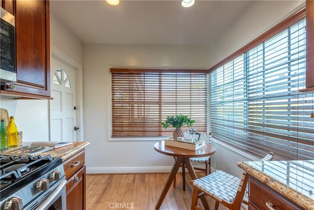 kitchen featuring appliances with stainless steel finishes, light stone countertops, light hardwood / wood-style floors, and a wealth of natural light