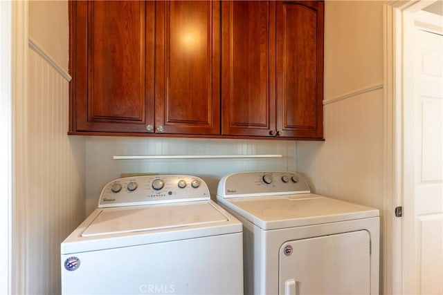 clothes washing area featuring cabinets and washing machine and clothes dryer