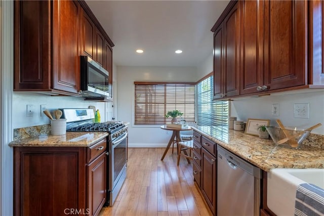 kitchen featuring light stone countertops, light hardwood / wood-style floors, and appliances with stainless steel finishes