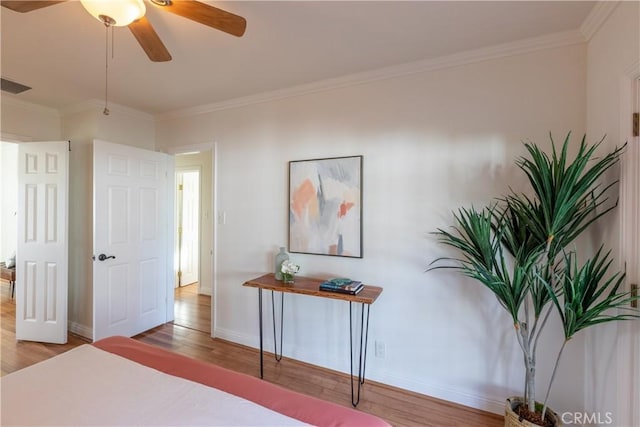 bedroom with wood-type flooring, ornamental molding, and ceiling fan