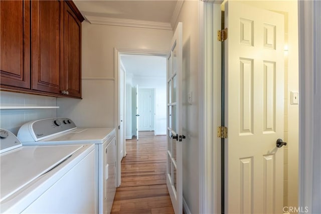 washroom with cabinets, independent washer and dryer, ornamental molding, and light wood-type flooring