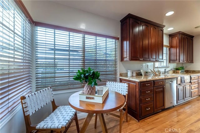 kitchen with stainless steel dishwasher, light stone countertops, sink, and a wealth of natural light