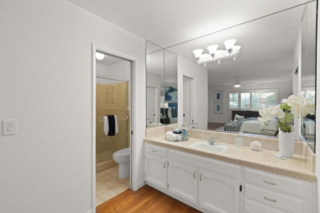 bathroom featuring ceiling fan, hardwood / wood-style floors, an enclosed shower, vanity, and toilet