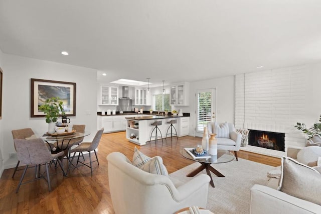 living room with a brick fireplace and wood-type flooring