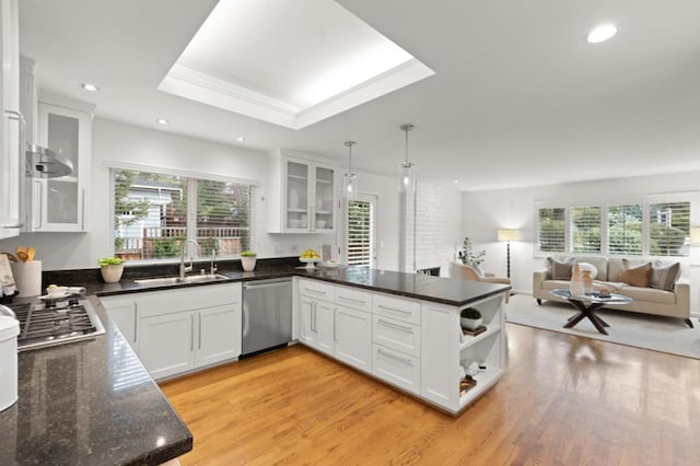 kitchen featuring sink, appliances with stainless steel finishes, kitchen peninsula, pendant lighting, and white cabinets