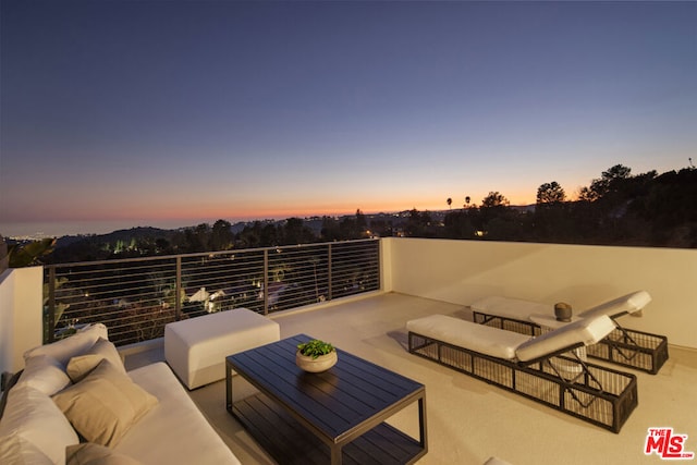 patio terrace at dusk with an outdoor living space and a balcony