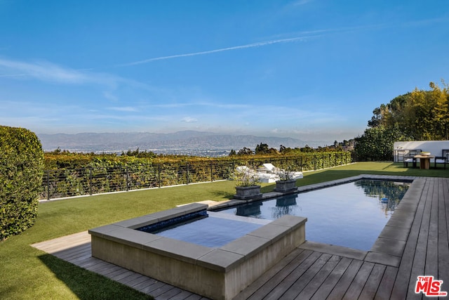 view of pool with an outdoor hot tub, a lawn, and a deck with mountain view