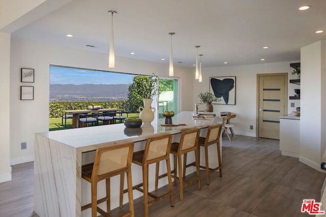 kitchen featuring a center island with sink, a mountain view, pendant lighting, and a breakfast bar area