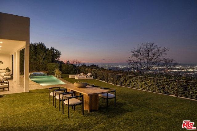 patio terrace at dusk featuring a fenced in pool and a lawn