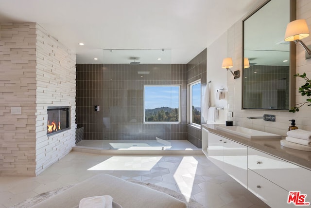 bathroom featuring tile walls, vanity, a stone fireplace, tile patterned floors, and walk in shower