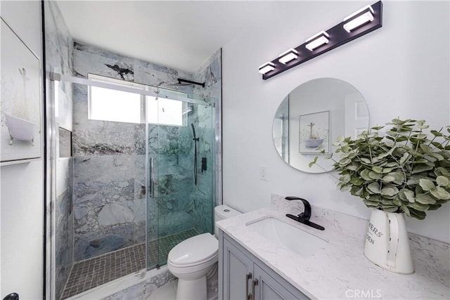 bathroom with vanity, a shower with door, and toilet