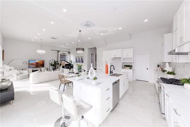 kitchen with pendant lighting, an island with sink, sink, white cabinets, and stainless steel appliances