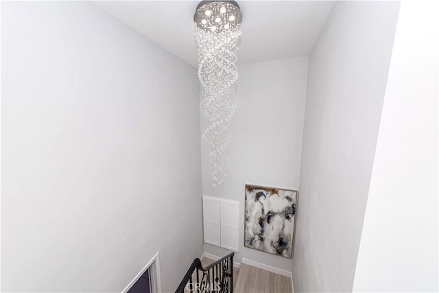 stairs with wood-type flooring and an inviting chandelier