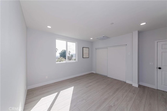 unfurnished bedroom featuring light wood-type flooring and a closet