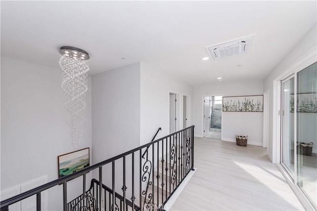 hall with light hardwood / wood-style flooring and a notable chandelier