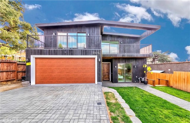 contemporary home with a garage, a front yard, and a balcony