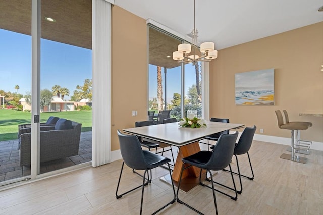 dining space featuring expansive windows, a chandelier, and light hardwood / wood-style floors