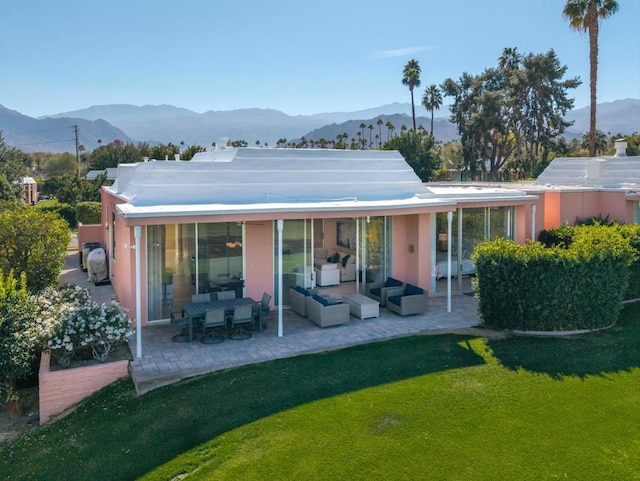 rear view of house featuring an outdoor hangout area, a mountain view, a patio, and a lawn