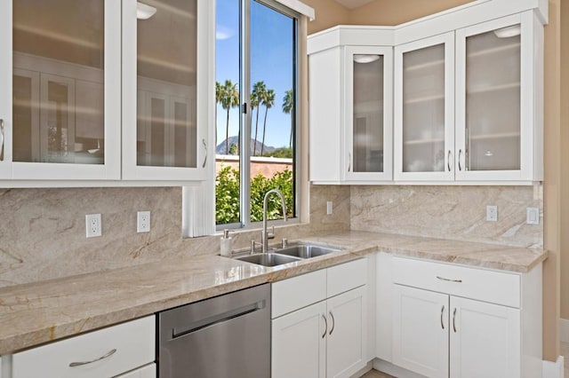 kitchen with light stone counters, stainless steel dishwasher, sink, and white cabinets