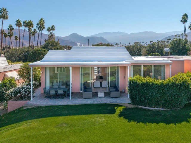 rear view of property featuring a mountain view, a lawn, and a patio area