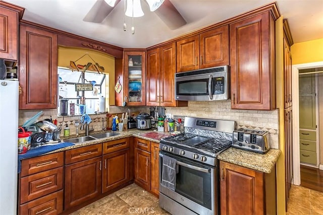 kitchen featuring sink, backsplash, light stone countertops, and appliances with stainless steel finishes