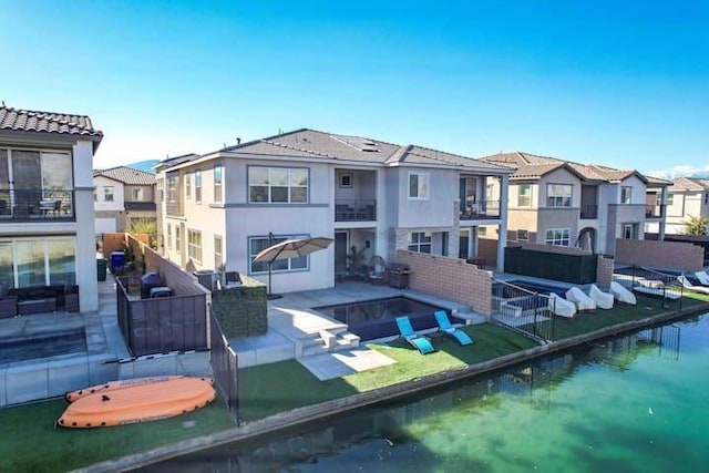 rear view of house with a water view, outdoor lounge area, and a patio area