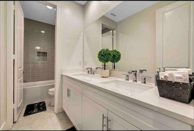 full bathroom with vanity, tiled shower / bath, tile patterned floors, and toilet