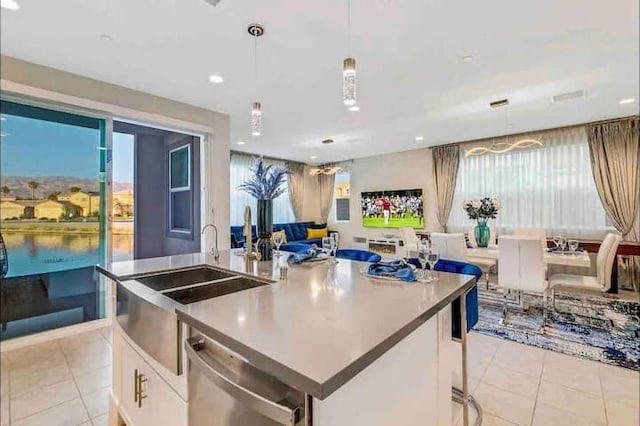 kitchen with white cabinetry, stainless steel dishwasher, decorative light fixtures, and a center island with sink