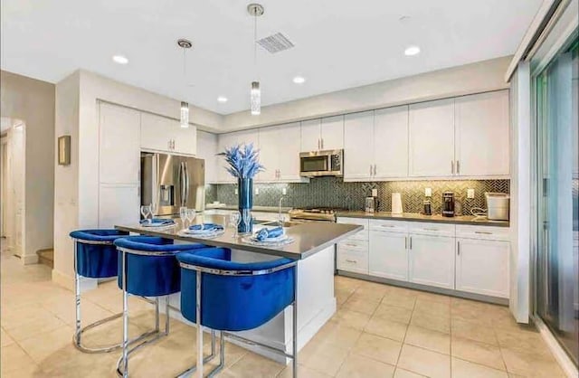 kitchen featuring hanging light fixtures, white cabinetry, appliances with stainless steel finishes, and tasteful backsplash