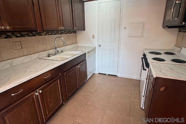 kitchen with light tile patterned flooring, tasteful backsplash, sink, dark brown cabinets, and white appliances