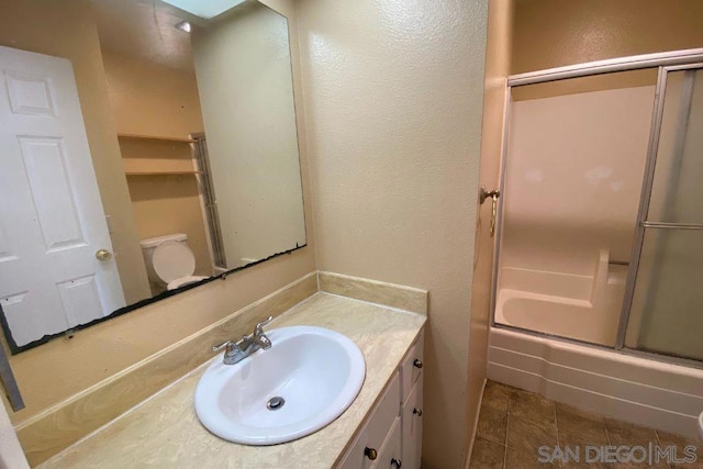 full bathroom with vanity, combined bath / shower with glass door, tile patterned floors, and toilet