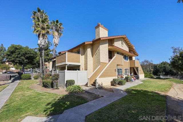 view of side of home featuring a balcony and a lawn